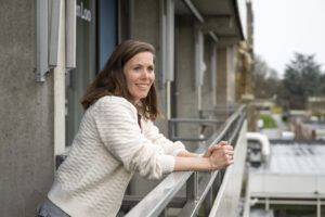 Portretfoto van Stadscoach Maaike bij een balkon.